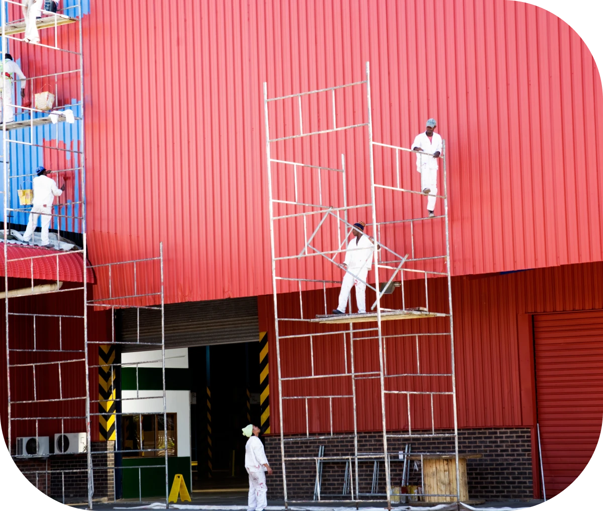 Workers on scaffolding painting red building